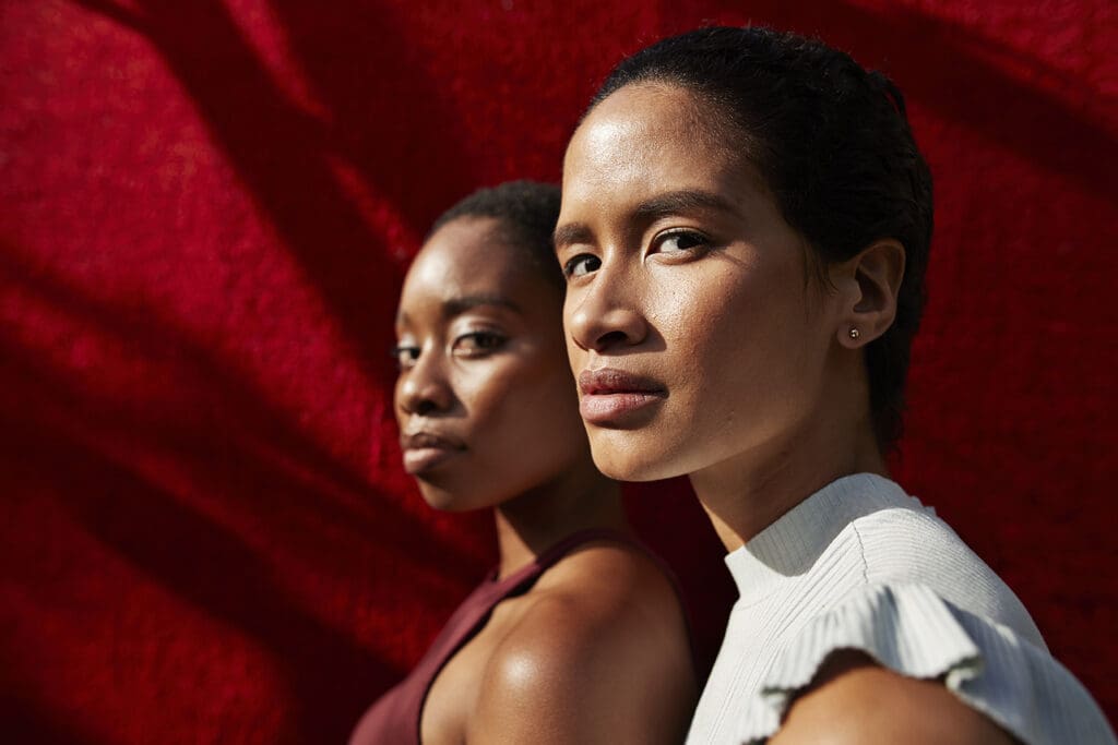 Portrait of young women standing against red wall